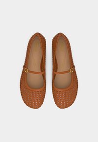 Καφέ πλεκτά δερμάτινα παπούτσια Mary Jane με ένα μόνο λουρί και αγκράφα, με μαξιλαρωμένες εσωτερικές σόλες, σε λευκό φόντο, θέα από πάνω.