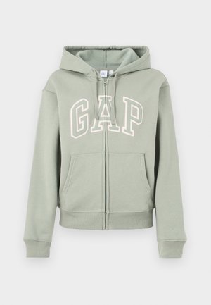 Gaiši zaļa kapuče ar rāvējslēdzēju priekšpusē, priekšējām kabatām, regulējamu kapuces auklu un lielu baltu "GAP" logotipu uz krūtīm.