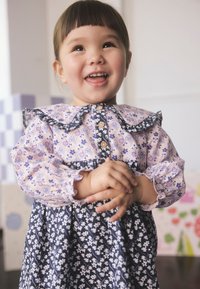 Lilleline kleit, millel on roosa ja lilla ülaosa, mustriline krae ja tumel sinine seelik valgete lilledega. Omadused hõlmavad nööpidega kinnitamist ja lopsakaid varrukaid.