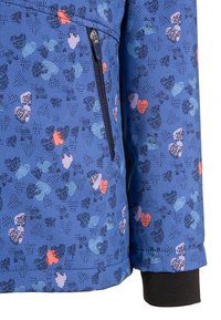 Veste bleue avec un motif texturé de cœurs colorés. Comprend une poche zippée et un poignet noir, fabriquée à partir d'un matériau lisse et léger.