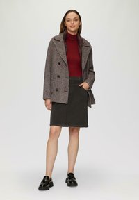 Manteau croisé en pied-de-poule gris et marron, associé à un col roulé bordeaux et une jupe gris foncé, complété par des mocassins noirs.