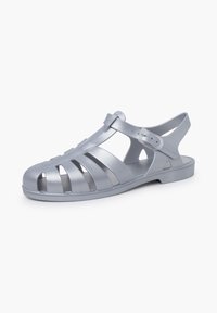 Silver plastic sandal with open-toe design, multiple horizontal cutouts, adjustable strap, and flat sole. Smooth, glossy texture.