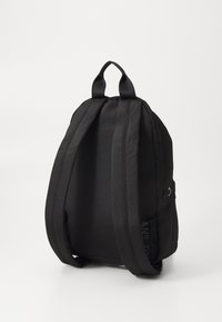 Sac à dos en tissu noir avec des bretelles réglables doubles, une forme de corps arrondie et une poche latérale extérieure. Design minimaliste sans embellissements.