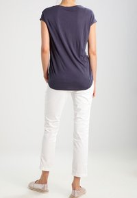 Top azul marino de manga corta con un corte holgado, combinado con pantalones blancos de pierna recta y zapatos de tela claros. Diseño simple, sin patrones.