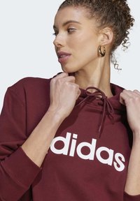 adidas Sportswear ESSENTIALS LINEAR - Mikina s kapucňou - shadow red   white