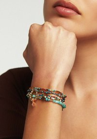 Bracelet multilayer avec des accents de turquoise, d'ambre et d'or ; différentes tailles et textures de perles ; comprend un charme en forme de fer à cheval avec une frange.