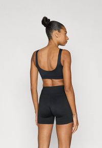 Fekete sportmelltartó és magas derekú rövidnadrág sima, rugalmas anyagból. A melltartón széles pántok és minimalista dizájn található.