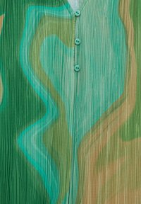Tela de patrón verde con textura plisada, que presenta espirales abstractas en tonos de verde y marrón claro, y tres botones turquesa.