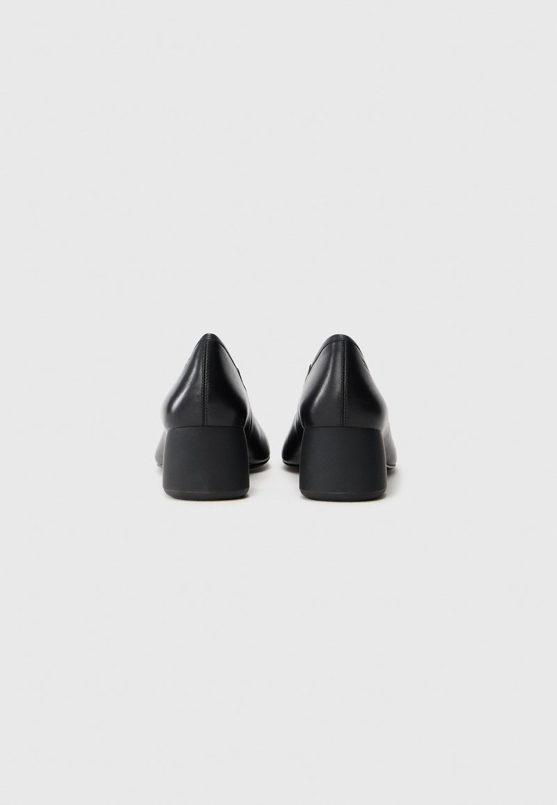 Black leather heeled shoes with a pointed toe and a medium block heel. Smooth texture, minimalist design without visible hardware or embellishments.