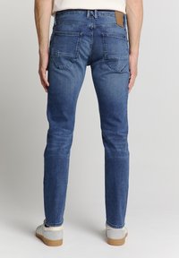Blauwe denim jeans met een slim fit, met twee achterzakken, een leren bruine label op de tailleband en subtiele vervagingen op de benen.
