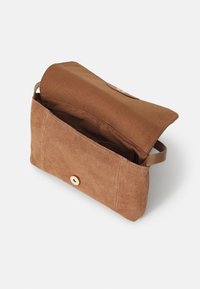 Brązowa zamszowa torba woreczkowa z klapką, złotym zatrzaskiem i boczną rączką. Wnętrze nie jest podszyte, co podkreśla jej pojemny design.