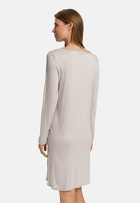 Dlouhý rukáv, šaty ke kolenům v světle šedé barvě, vyrobené z hladkého materiálu s kulatým výstřihem a jemně zakřiveným spodním lemem.