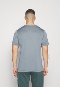 Camiseta gris de manga corta hecha de una tela suave y ligera con un escote redondeado. Presenta un ajuste regular y un diseño sencillo.