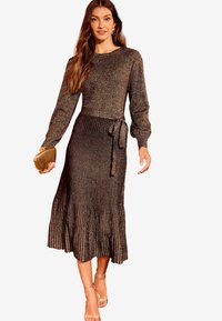 Metallisch schwarzes, geripptes Kleid mit langen Ärmeln, einem runden Ausschnitt und einem Bindeband in der Taille. Ausgestellt Rock mit einem dezenten Glanz.