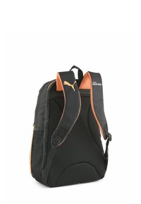 Czarny plecak z pomarańczowymi akcentami, teksturowanymi paskami z siateczki i wyściełanym plecami. Posiada logo i boczną kieszeń do przechowywania.