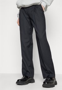 Svarta skräddarsydda byxor med rak passform, med framfickor och sidfickor, tillverkade av ett mjukt och lätt material.