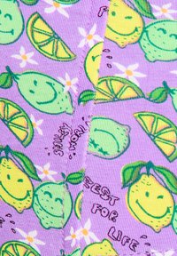 Tissu violet avec un motif de citrons et de limes souriants, de feuilles vertes et de fleurs blanches, accompagné du texte "ZESTE DE VIE".