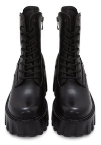 Bottines noires avec un extérieur en cuir lisse, dotées d'une haute plateforme, d'un système de laçage à l'avant et d'une fermeture à glissière sur le côté. Semelle texturée avec des nervures.