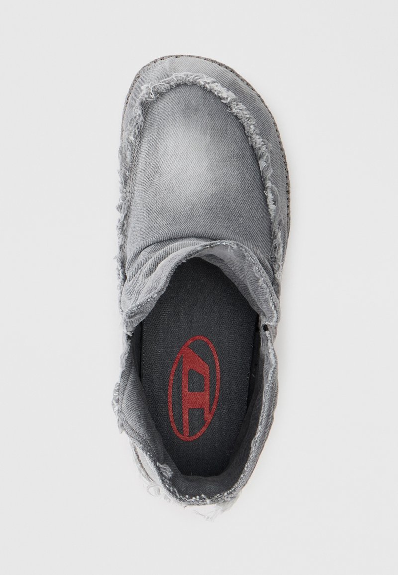 Scarpa slip-on grigia con bordi sfilacciati, tomaia in tessuto e soletta nera con logo rosso. Forma complessiva arrotondata e design casual.
