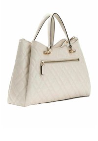 Borsa trapuntata beige con ferrature dorate, due manici e tasca frontale con zip. Presenta una forma strutturata e una texture liscia.