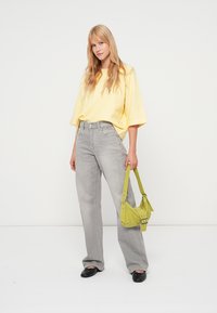 Dzeltena pārlielu izmēru T-krekls, pelēnas platajiem džinsiem, melnas dzīvokļpapēžs kurpes un maza laima zaļa soma ar sudraba detaļām. Gluda tekstūra, brīvs piegriezums.