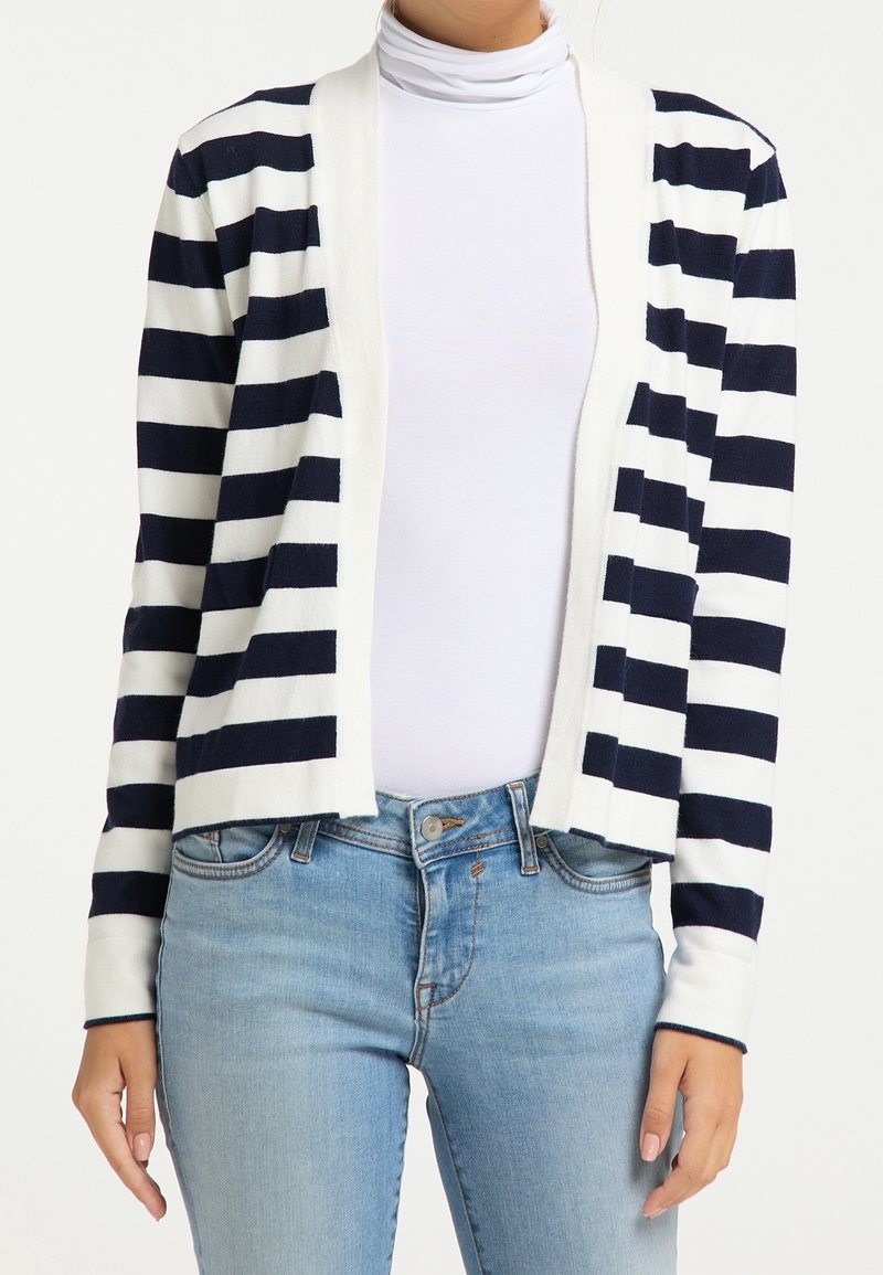 Cardigan rayé bleu marine et blanc, à ouverture devant, en tissu tricoté doux, avec des poignets contrastés, porté sur un haut blanc et un jean en denim.