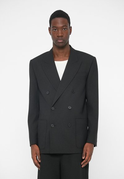 Blazer noir à double boutonnage avec revers crantés, deux poches avant et six boutons. Fabriqué en tissu texturé, au style décontracté.