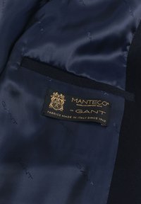 Dark blue jacket lining with a black and gold label reading "Manteco for GANT, fabrics made in Italy since 1943."