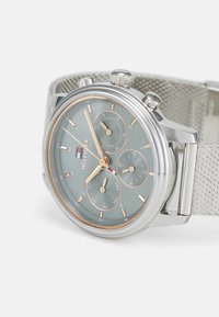 Montre en argent avec un cadran gris texturé, trois sous-cadrans, des accents en or rose et un bracelet en maille. Les caractéristiques comprennent une couronne proéminente et des poussoirs.