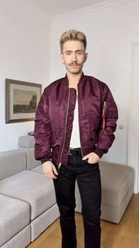 Bordo bomber jakna z zadrgo, rebrastimi manšetami in žepom na rokavu. Oblečena čez belo srajco in črne hlače.