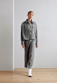 Gray plaid, cropped jacket with large buttons and a chest pocket, paired with wide gray trousers and white footwear. Smooth textures.
