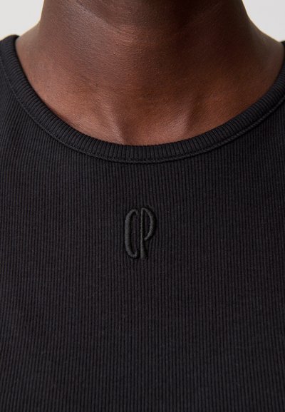 Top de punto acanalado negro con cuello redondo. Presenta un logo bordado "CP" en el cuello. Tejido texturizado con un ajuste ceñido.