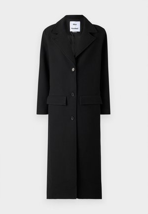 Czarny wełniany płaszcz z długimi rękawami, z wcięciem przy kołnierzu i zapięciem na trzy guziki. Posiada dwie przednie kieszenie i prostą sylwetkę.