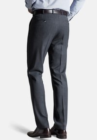 Grijze tailor-made broek met een gladde textuur, slim fit en twee achterzakken, aangevuld met een leren brown riem en donkere schoenen.