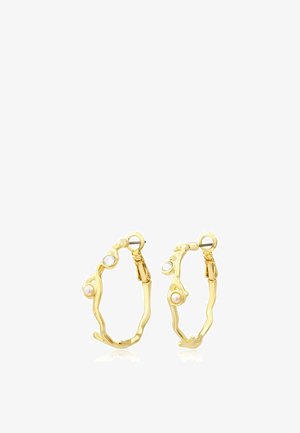 Boucles d'oreilles en forme d'anneaux dorés avec un design torsadé irrégulier, chacune ornée d'une petite perle et d’un accent en pierre précieuse claire près du fermoir.