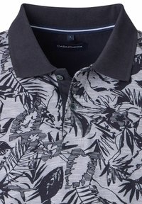 Koszulka polo z krótkim rękawem w szarym kolorze z bawełny, z czarnym wzorem liści. Posiada czarny prążkowany kołnierzyk, listwę z guzikami oraz niebieskie akcenty.