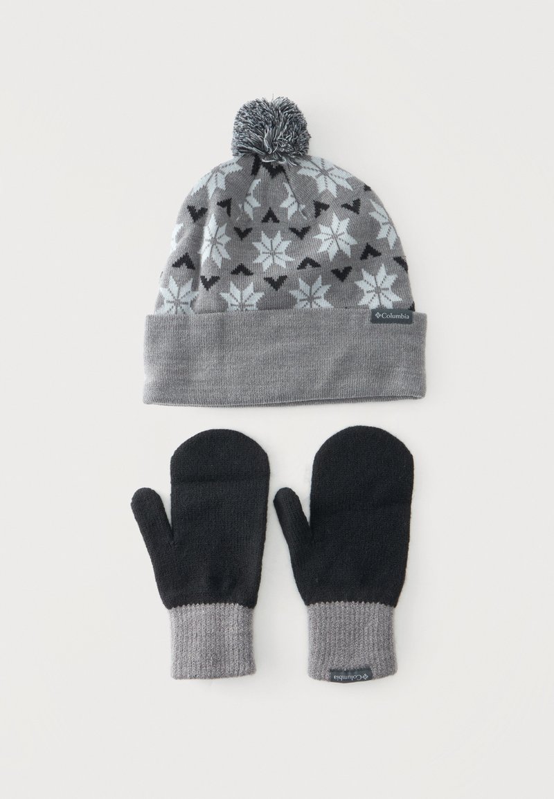 Bonnet d’hiver gris et noir avec motif flocon de neige et pompon, accompagné de moufles noires avec poignets gris, tous deux avec des étiquettes de la marque Columbia.