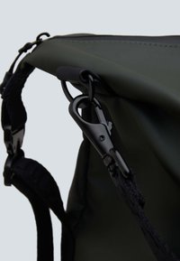 Borsa a spalla verde realizzata in un tessuto resistente, con accessori neri e un prominente attacco a clip sul lato per una chiusura sicura.