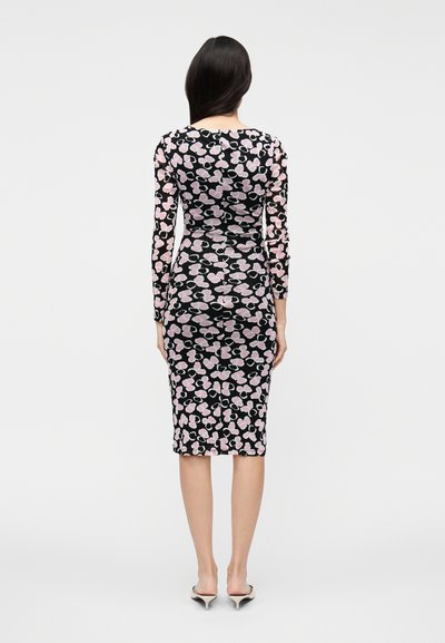 Vestido bodycon de manga comprida em preto com padrão floral rosa. Comprimento médio, silhueta ajustada com decote redondo e textura suave.