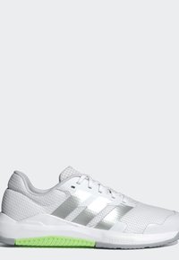 Chaussure de sport blanche avec des rayures argentées, dessus en mesh, design à lacets et accent vert sur la semelle, vue de profil sur fond gris.