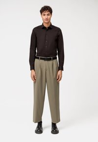 Maglietta nera a maniche lunghe con colletto button-down, pantaloni kaki plissettati, cintura nera e scarpe nere. Design semplice e moderno con vestibilità su misura.