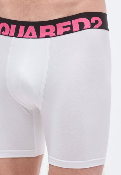 Boxer briefs blancos con una cinturilla negra que presenta el logo "DSQUARED2" en rosa. Fabricados con una tela suave sin patrones visibles.