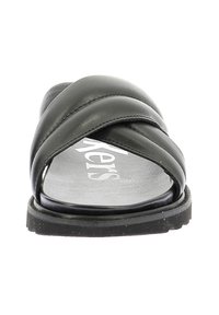 Sandali in pelle nera con cinturini incrociati, suola piatta e fondo testurizzato. Progettati per comfort e uso quotidiano.