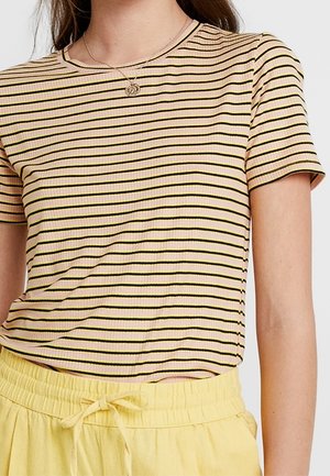 Camiseta de rayas con textura acanalada, mangas cortas, escote redondo, con rayas horizontales en rosa y negro. Combinada con pantalones de color amarillo claro.