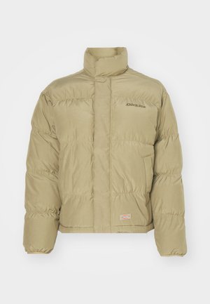Chaqueta acolchada caqui con cuello alto, puños elásticos y patrón de acolchado horizontal. Presenta el logo de "Dickies" en la parte frontal.