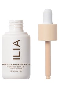 ILIA Super Serum Skin Tint SPF 30 i en vit flaska med brun text, med en beige dropper för dosering av vätska. 30 ml kapacitet.
