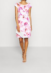 Sukienka w kwiatowy wzór z krótkimi rękawami, w odcieniach różu i fioletu na białym tle. Zawiera biały pasek i pasującą kopertówkę.