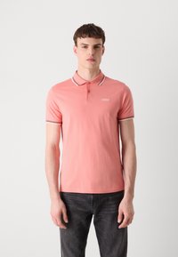 Polo rose avec des bordures de col contrastantes et des manches courtes. Présente un petit logo sur la poitrine gauche. Fabriqué en matériau lisse et léger.