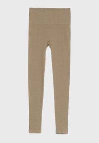 Leggings beige de textura acanalada con una cintura ancha y elástica y una silueta ajustada. Presentan una pequeña abertura en la parte frontal.