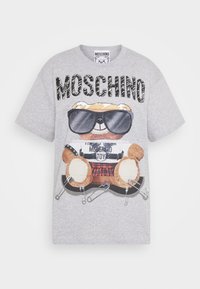 Grå t-shirt med kort ärm som har en tecknad björn i solglasögon, säkerhetsnålar och ett rutigt mönster med "MOSCHINO" i fet stil.